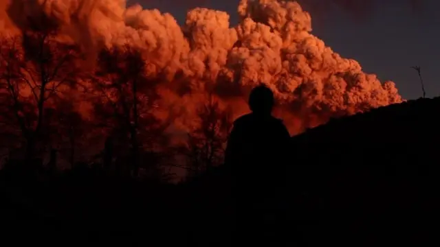Hombre fumando frente a nube de ceniza